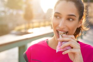 A woman eats a granola nut bar while on a jog. Healthy snacks are meant for people on the move who want to keep moving better.